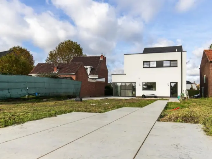 Licht betonterras met gezaagde vlakken bij een witte woning in Diepenbeek
