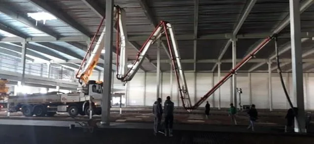 Betonpomp met gevouwen giek tijdens betonwerken in een hal