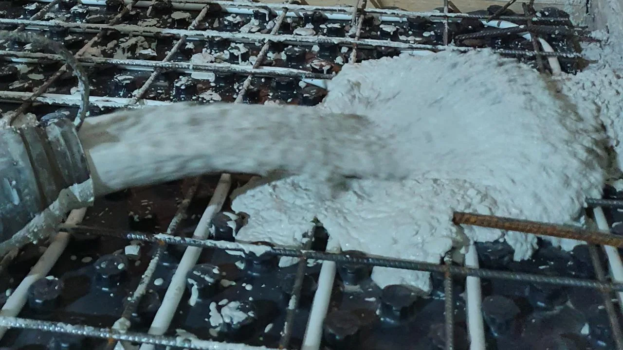 Verse witte beton wordt gestort tussen de zichtbare wapening