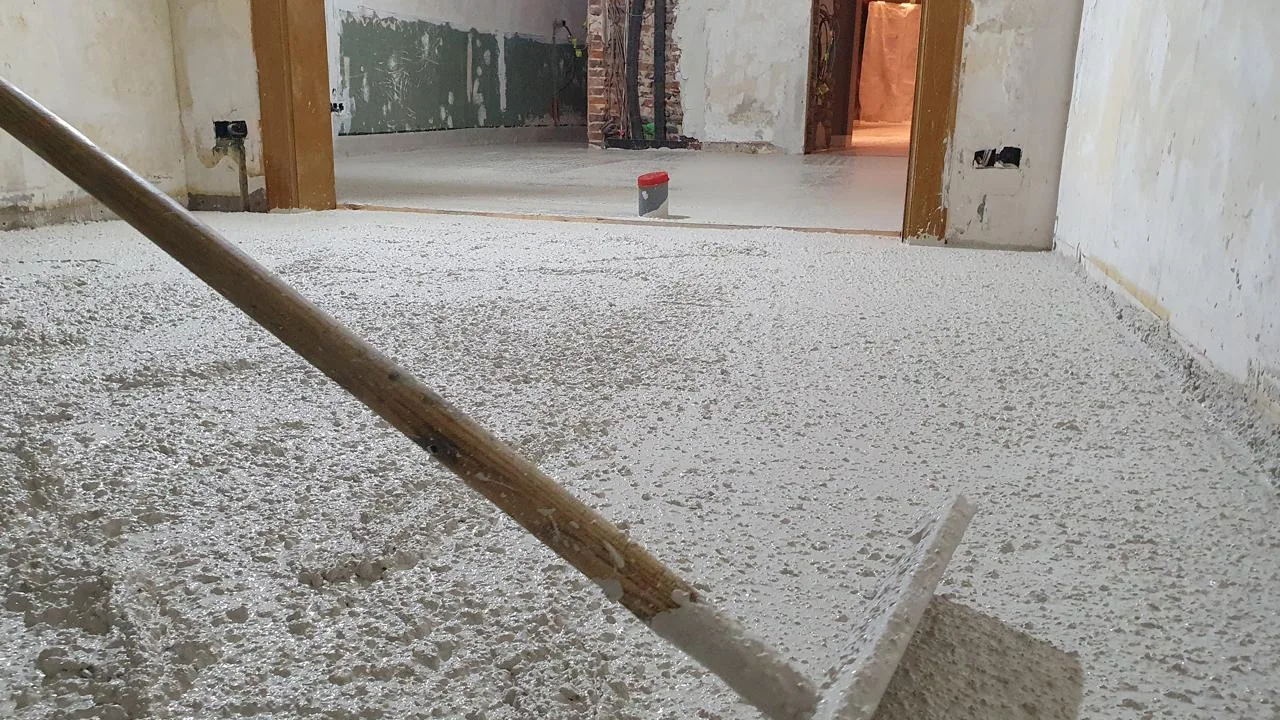 Ruw verdeeld wit beton tijdens het vlakzetten van de vloer