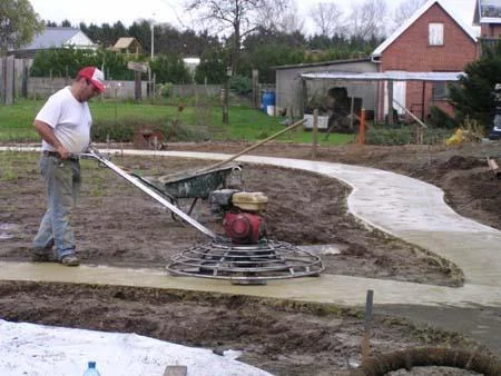 Medewerker van Glansbeton poliert het gebogen tuinpad met een machine