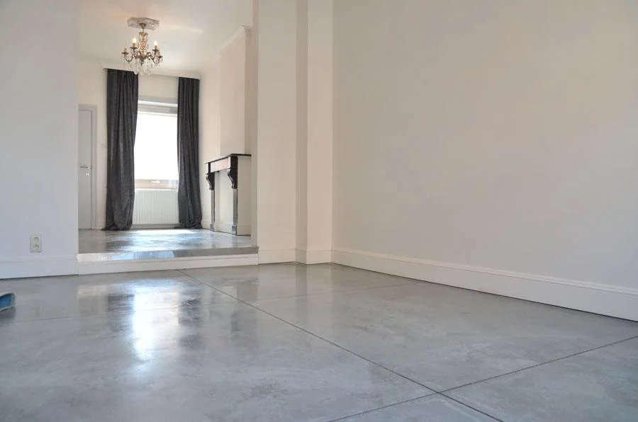 Cementkleurige betonvloer met gezaagde vlakken in een rijwoning in Hasselt