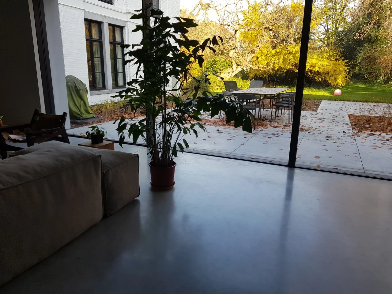 Gepolierde betonvloer bij de grote ramen met uitzicht op de tuin