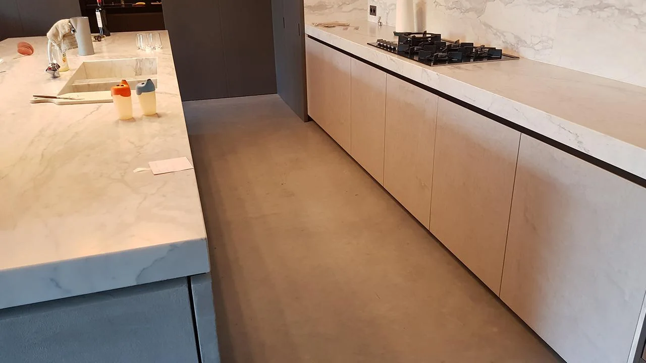 De betonvloer tussen het keukeneiland en de houten keukenfronten in Leuven