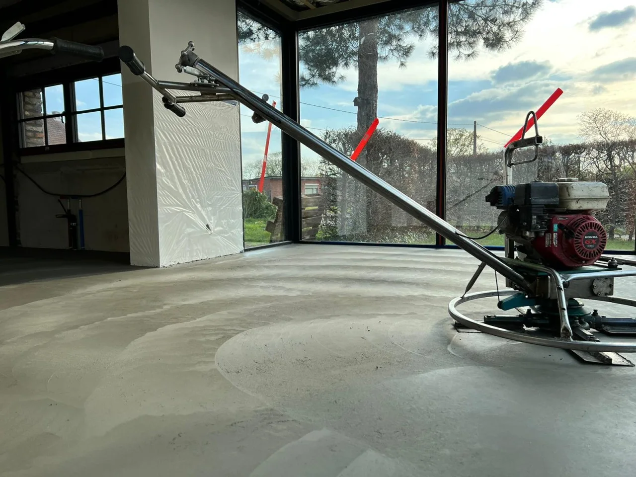 Poliermachine op een verse betonvloer bij de ramen van een woning