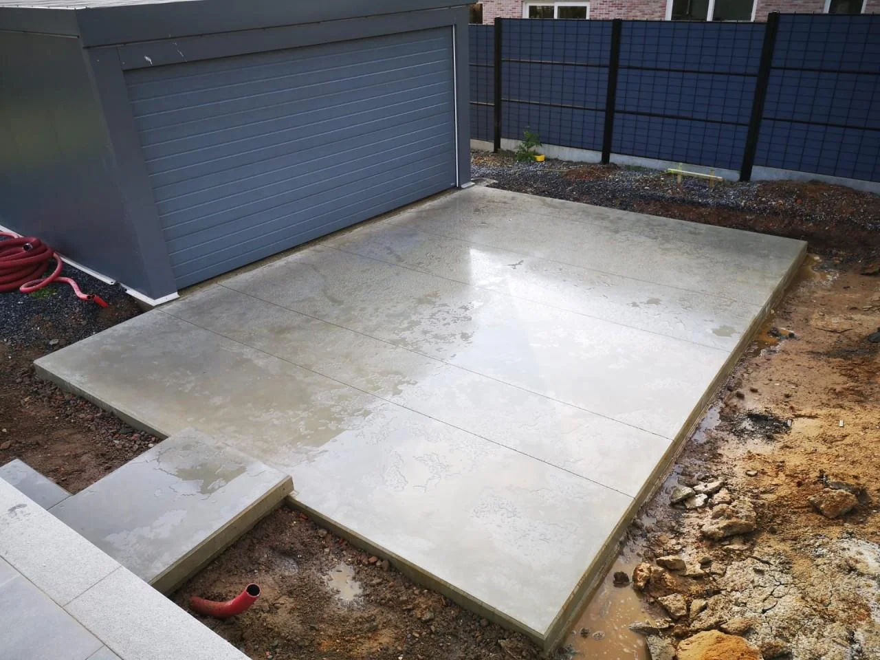 Betonnen oprit voor een garagepoort tijdens de uitvoering, met zichtbare randen en voegen