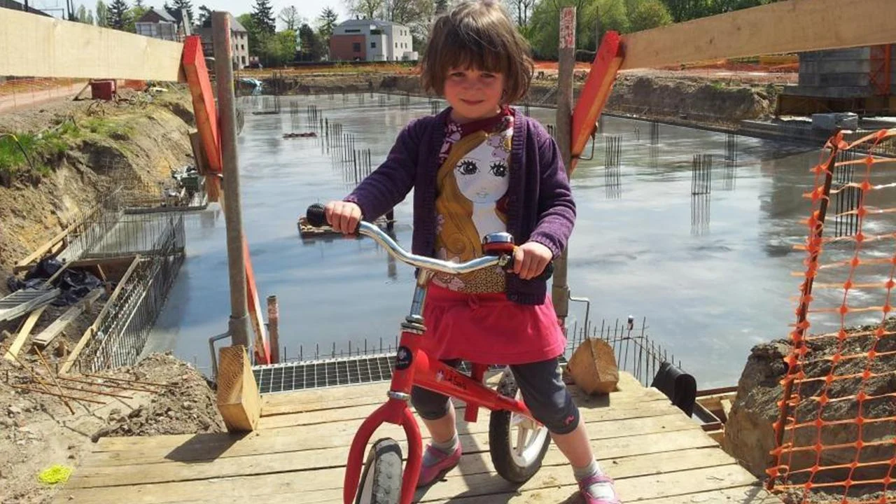 Persoonlijk werfbeeld met een loopfiets en een grote betonvloer in de bouwput op de achtergrond