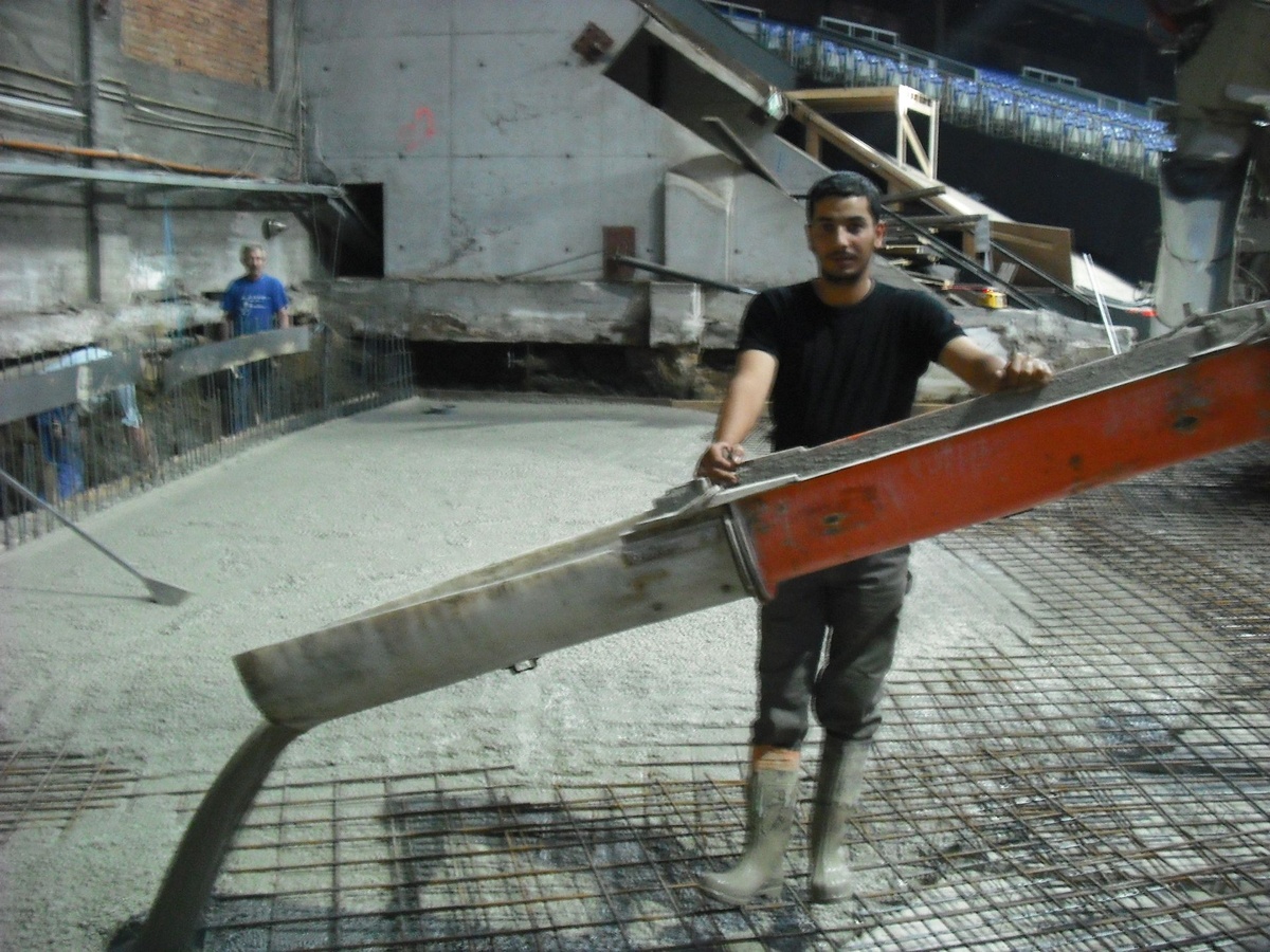 Medewerker verdeelt vers beton tijdens de uitvoering in het Sportpaleis.