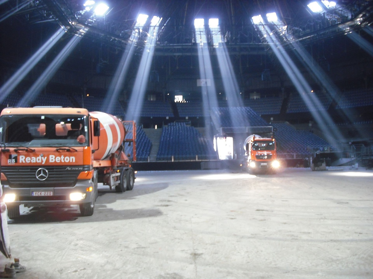 Betonwagens en lichtinval in de evenementenhal tijdens de werken.